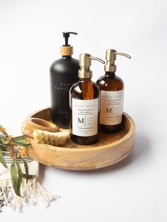 two soap dispensers sitting on top of a wooden tray