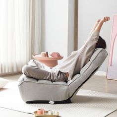 a woman laying on top of a chair in a living room