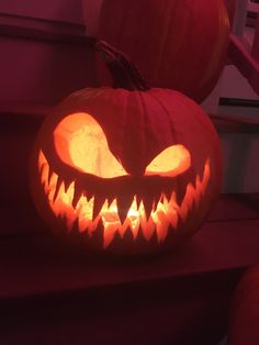 two jack o lantern pumpkins sitting on top of a wooden step with their faces carved into them