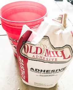 two red buckets sitting next to each other on top of a cement floor covered in white paper