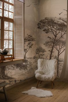 a white chair sitting in front of a window next to a wall with trees on it