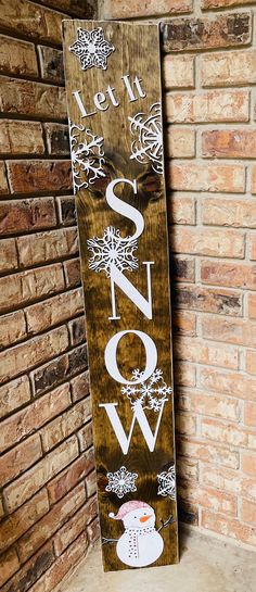 a wooden sign with the word snow written in white on it next to a brick wall