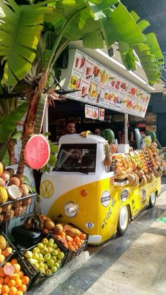 a yellow and white vw bus parked next to a bunch of fruit on display