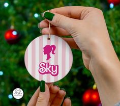 a woman holding up a pink and white ornament with the word sky on it