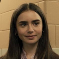 two people standing next to each other in front of a brick wall and looking at the camera