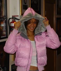 a woman in a pink jacket is holding her hood up