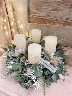 a wreath with candles and greenery on a pink blanket in front of a wooden wall