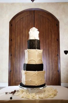 a three tiered cake sitting on top of a table next to a wooden door