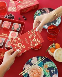 two hands holding up a red card next to plates and bowls with food on them