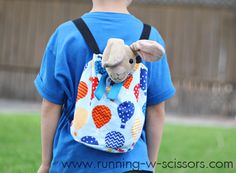 a young boy wearing a backpack with a stuffed animal in it's back pocket