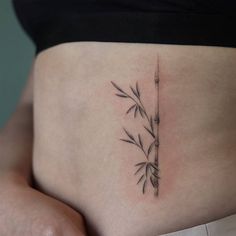 a woman's stomach with a bamboo plant tattoo on her lower side ribcage