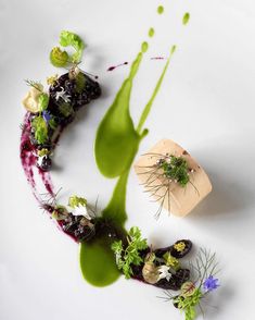 a white plate topped with different types of food and garnished in green sauce