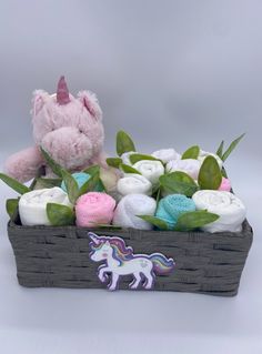 a stuffed unicorn sitting next to a basket filled with blankets and crocheted toys