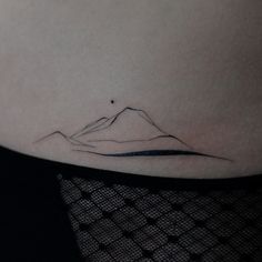 a woman's stomach with a small mountain tattoo on her left side ribcage