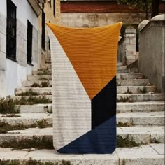 an orange, white and blue blanket sitting on top of some steps