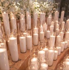 many white candles are lined up on a table