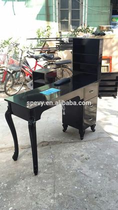 a black desk with drawers and a bicycle parked next to it