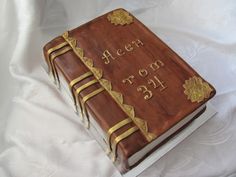 a cake made to look like a book with gold trimmings on the cover