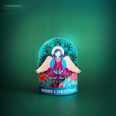 a christmas card with an angel sitting on top of it, in front of a green background