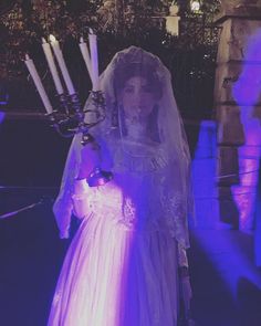 a woman in a white dress holding a candelabra with candles on it