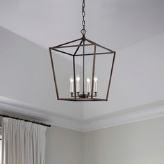 a chandelier hanging from the ceiling in a room with white walls and curtains