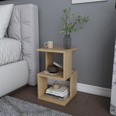 a corner table with a plant and books on it in front of a white couch