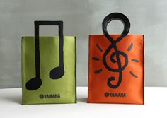 two bags with music notes painted on them, one is orange and the other is green