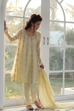 Party wear eastern dress in pastel yellow color is designed beautifully in frock style. Part wear eastern dress has floral thread work all over Party Sharara In Organza With Naqshi Detailing, Party Sharara With Naqshi In Organza, Organza Sharara With Naqshi For Party, Cream Dress With Zari Work For Festive Occasions, Festive Cream Dress With Zari Work, Cream Bollywood Dress With Resham Embroidery, Yellow Organza Sets With Chikankari Embroidery, Yellow Chikankari Embroidery Party Dress, Yellow Chikankari Party Dress