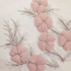 four pink beaded flowers on white fabric