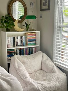 a white bed sitting next to a book shelf filled with books