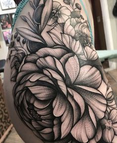 a black and white flower tattoo on the back of a woman's shoulder