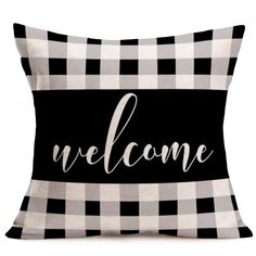 a black and white pillow with the word welcome on it in cursive font