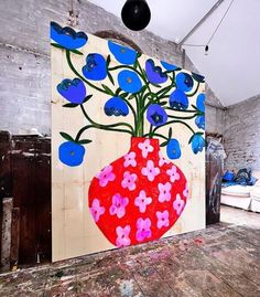 a painting on the wall with blue flowers in a red vase painted on it's side