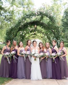 a group of women standing next to each other in front of a lush green archway