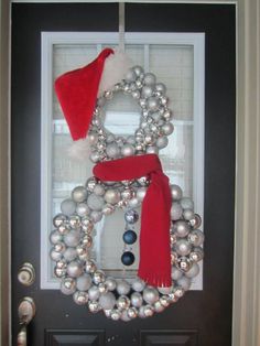 a door decorated with ornaments and a santa hat on it's head, sitting in front of a black door