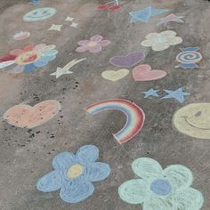 chalk drawings on the ground with flowers, hearts, stars and a rainbow painted on it