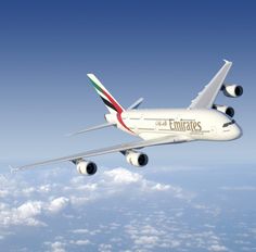 an emirates airplane flying in the sky above clouds