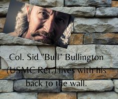 a brick wall with an image of a man's face on it and the words col sid bulllington usme re lives with his back to the wall