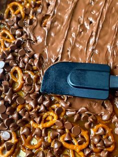 a spatula filled with chocolate and pretzels on top of a sheet of food