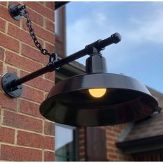 an outdoor light hanging from the side of a brick building