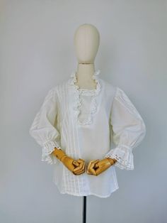 Vintage white Austrian blouse. Featuring puff sleeves, eyelet ruffle collar and cuffs and delicate pleats. Fastens with three buttons on the bodice. Fabric: 50% cotton 50% polyester Brand: Kruger Dirndl Perfect condition Fits size UK 14 or smaller depending on desired fit. Mannequin is size UK 6. Measurements (taken laid flat and doubled when applicable): Bust: 42" / 106cm Hemline: 44" / 112cm Shoulders: 15" / 38cm Inner sleeve: 12" / 30cm Length: 26" / 66cm Message if you have any questions 😊 Cotton Blouse With Pleated Sleeves For Daywear, Cotton Long Sleeve Blouse With Pintucks, White Feminine Peasant Top With Ruffles, Elegant Ruffled Peasant Top For Daywear, Daywear Blouse With Bishop Sleeves And Ruffles, Daywear Blouse With Ruffles And Bishop Sleeves, Cotton Lantern Sleeve Blouse For Daywear, Classic Cotton Blouse With Ruffles, Cotton Ruffle Puff Sleeve Blouse