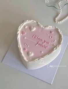 a heart shaped cake on top of a piece of paper next to a beaded necklace