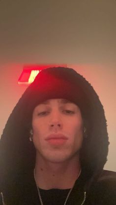 a young man wearing a black hoodie with a red light above his head