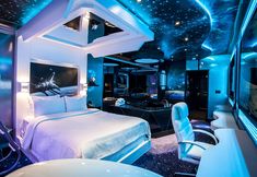 a bedroom with a bed, desk and chairs in the room that has stars on the ceiling