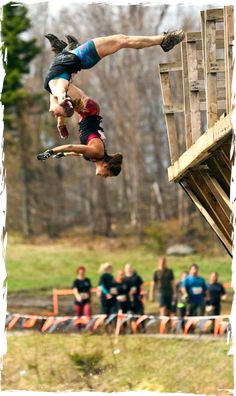 two men are doing tricks in the air while others watch from the sidelines behind them