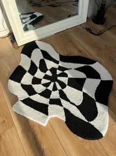 a black and white rug sitting on top of a wooden floor next to a mirror