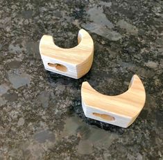 two small wooden toothbrush holders sitting on top of a granite countertop next to each other