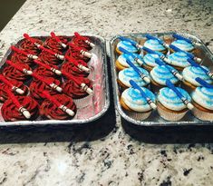 two trays filled with cupcakes sitting on top of a counter