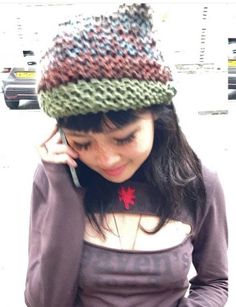 a woman talking on her cell phone while wearing a knitted hat