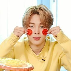 a young man holding two slices of pizza in front of his eyes